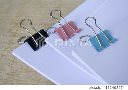 Close up of paper clips pastel clipping blank paper on wooden table. Close up of paper clips pastel clipping blank paper on wooden table. 112402474