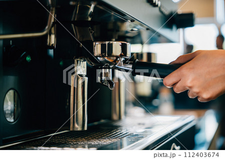 At restaurant or pub coffee machine brews fresh tasty coffee. Step by step guide to professional coffee making process. Close up of machine hand holding handle pouring espresso. 112403674
