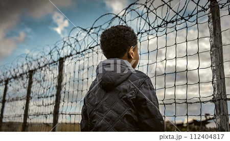 Black Child at the State Border with Metal Fence and Barbed Wire - Generative Ai 112404817