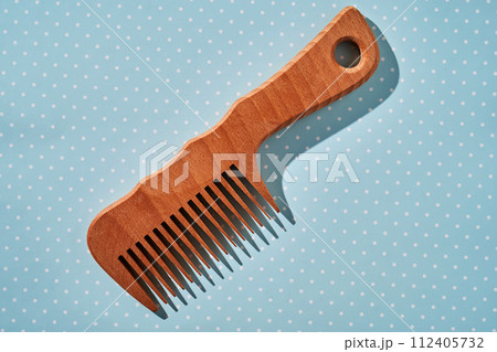 Wooden comb on a blue polka dot background. Wooden comb on a blue polka dot background. 112405732