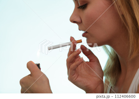Girl using lighter to light cigarette. 112406600