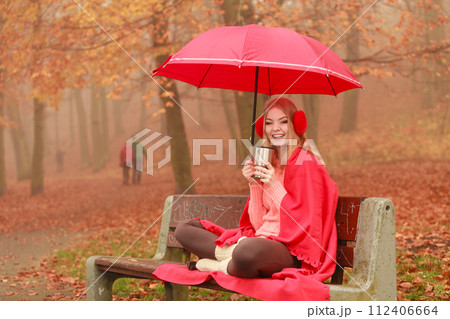 Woman drinking hot coffee relaxing in autumn park Woman drinking hot coffee relaxing in autumn park 112406664