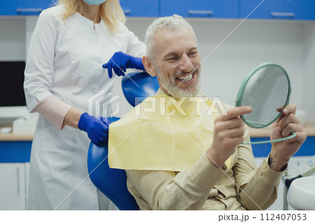 Male smiling during her dental treatment at dentist. 112407053