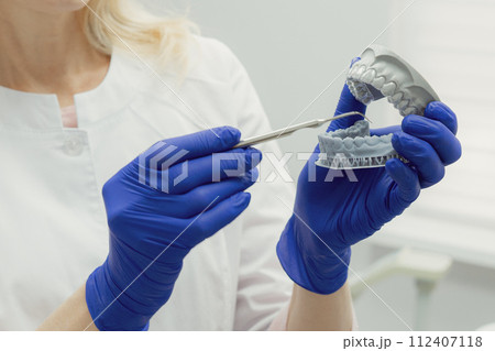 Woman working in dental clinic with patient sitting in chair and doctor in background. Woman working in dental clinic with patient sitting in chair and doctor in background. 112407118