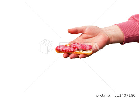 Sandwich with sausage in the hand of a middle-aged woman. The concept of the world food crisis associated with the war in Ukraine. Isolated on white background Sandwich with sausage in the hand of a middle-aged woman. The concept of the world food crisis associated with the war in Ukraine. Isolated on white background 112407180