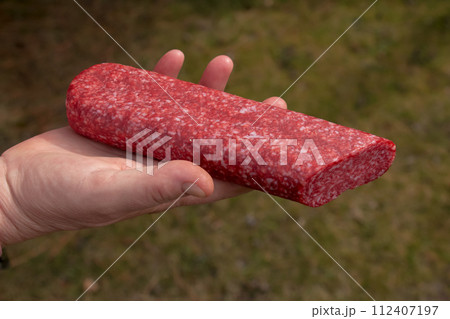 Sausage in the hand of a middle-aged woman. The concept of the world food crisis associated with the war in Ukraine Sausage in the hand of a middle-aged woman. The concept of the world food crisis associated with the war in Ukraine 112407197