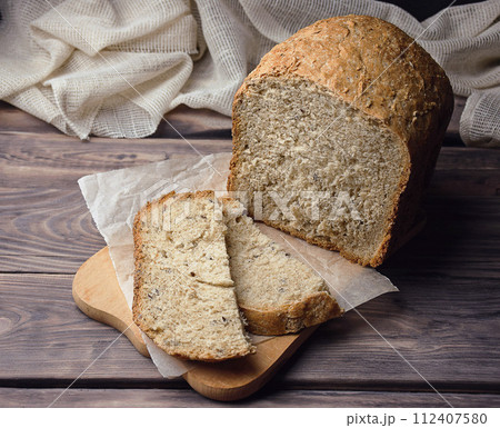 Homebaked bread sourdough  bread with seeds cut into slices lies on a cutting board. Loaf of bread  112407580