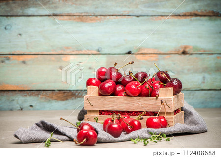 Red ripe cherries in small wooden box 112408688