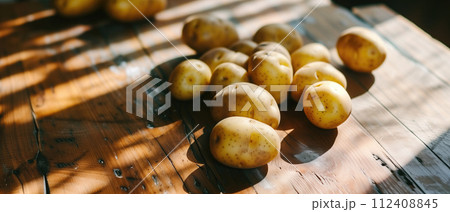 AI-generated content. Fresh potatoes scattered on a rustic wooden table in sunlight banner, representing organic farming, local produce, and food ingredients, suitable for cooking tutorials, recipe 112408845