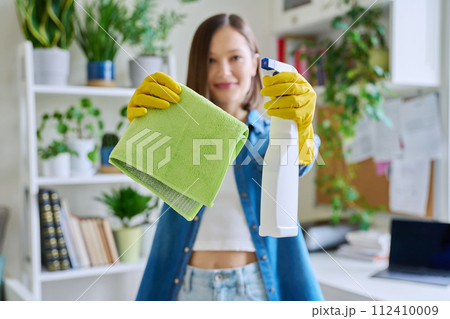 Close-up of cleaning rag with detergent spray in hands of young woman 112410009