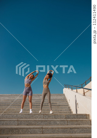 Young sportswomen in tracksuit are stretching outdoor and preparing to jogging. Healthy life concept Young sportswomen in tracksuit are stretching outdoor and preparing to jogging. Healthy life concept 112411490