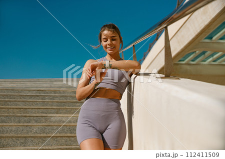 Smiling fit woman looking at smartwatch and counting calories burned. Healthy life concept 112411509