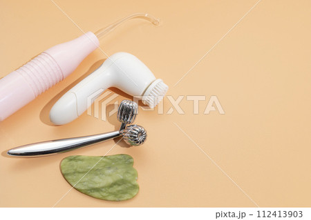 Flatly Mockup Skin Care Products. Facial Tool Gua Sha, Darsonval Skin Beauty Device, Sculpt Facial Roller, Anti-Aging, Facial Cleansing Brush on Beige Background. Copy Space For Text. Horizontal Plane 112413903