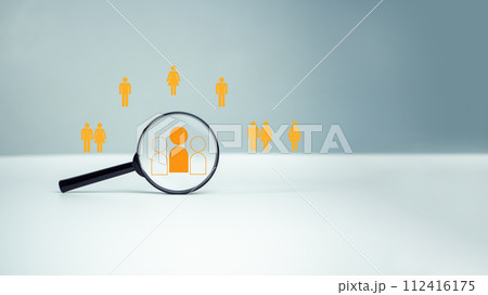 Customer group icons in a magnifying glass placed on a white background represent the selection of business goals, target customers, Marketing plans and strategies, customer-centric strategies. 112416175