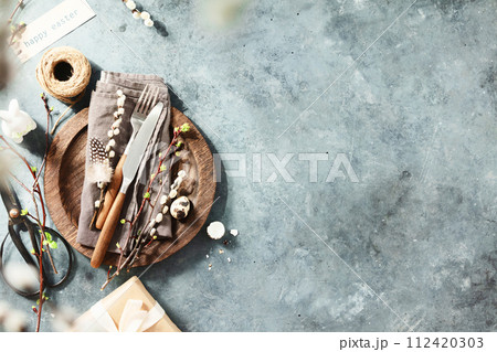 Easter table setting with spring flowers and cutlery on dark blue background top view flat lay Easter table setting with spring flowers and cutlery on dark blue background top view flat lay 112420303
