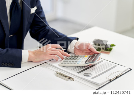 不動産に関するお金の計算をするビジネスマン 不動産に関するお金の計算をするビジネスマン 112420741