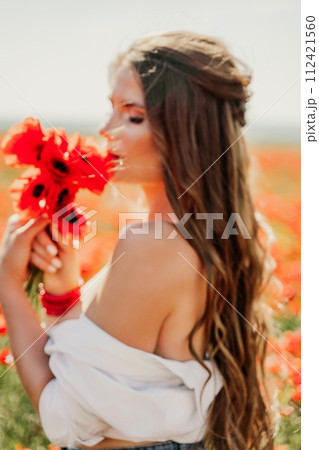 Woman poppies field. Side view of a happy woman with long hair in a poppy field and enjoying the beauty of nature in a warm summer day. 112421560
