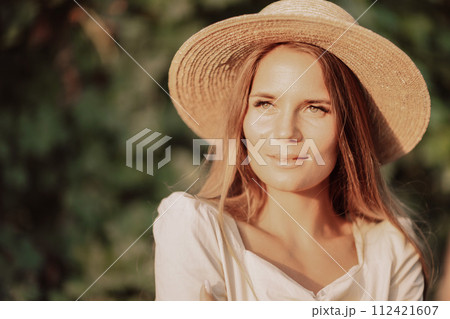 Woman with straw hat stands in front of vineyard. She is wearing a light dress and posing for a photo. Travel concept to different countries 112421607