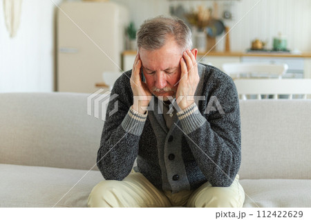 Headache pain. Unhappy middle aged senior man suffering from headache sick rubbing temples at home. Mature old senior grandfather touching temples experiencing stress. Man feeling pain hurt in head 112422629
