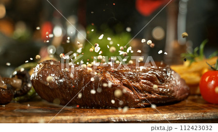 Close-up of falling salt on tasty beef steak in kitchen. 112423032
