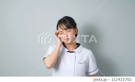 頭痛に悩む白衣を着た女性 112423702