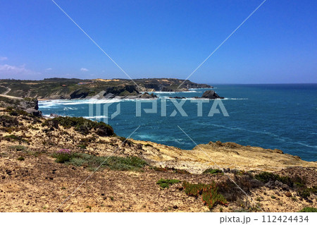 Ocean waves hit the jagged cliffs on a sunny day. Ocean waves hit the jagged cliffs on a sunny day. 112424434
