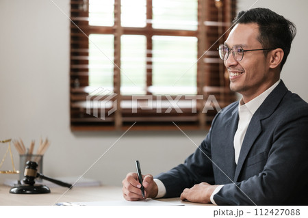 Asian lawyer man working on table office Writing a document, law and justice concept. 112427088