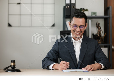 Asian lawyer man working on table office Writing a document, law and justice concept. 112427091