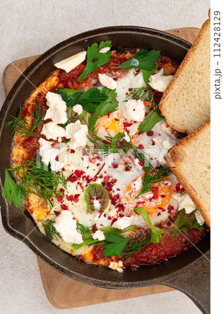 Pan of middle eastern dish shakshuka with toasts Pan of middle eastern dish shakshuka with toasts 112428129