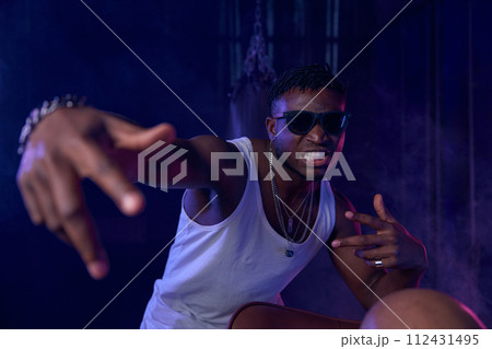 Young guy rapper posing for camera in neon light 112431495
