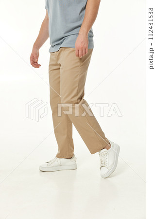 man wearing white sneakers and casual beige pants on studio background. side view man wearing white sneakers and casual beige pants on studio background. side view 112431538
