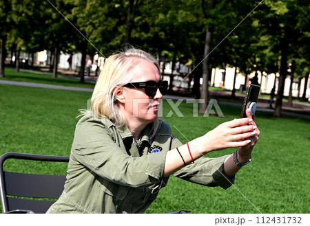 A girl takes a selfie in the park. A fashionable girl takes a selfie on a smartphone 112431732
