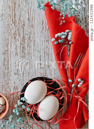 Create an Easter composition of Easter quail eggs and flowers on a wooden background. A gentle greeting card for the Easter holiday.Top view, copy location, flat layout. 112431996