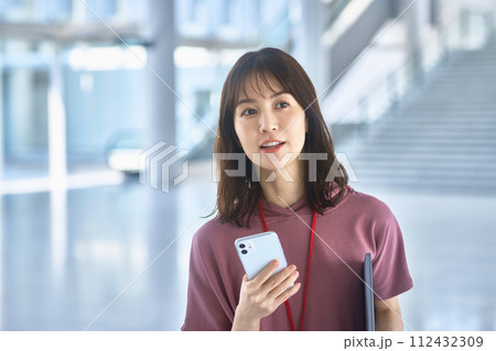 オフィスでスマホを操作する私服の若いビジネスウーマン 112432309
