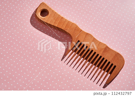 Wooden comb on a pink polka dot background. Wooden comb on a pink polka dot background. 112432797