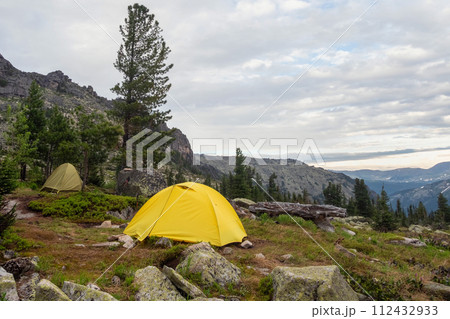 landscape with two tents on forest hill among rocks 112432933