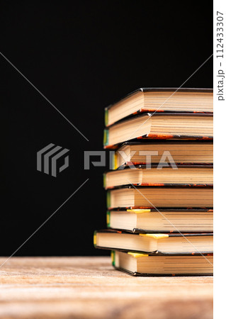 Stack of old books on a black background. Wisdom and knowledge, love of reading. 112433307
