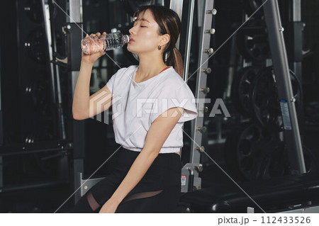 トレーニングジムで水を飲む女性 トレーニングジムで水を飲む女性 112433526