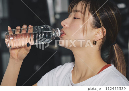 トレーニングジムで水を飲む女性 トレーニングジムで水を飲む女性 112433529