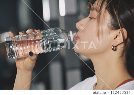 トレーニングジムで水を飲む女性 トレーニングジムで水を飲む女性 112433534
