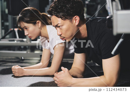 トレーニングジムで真剣な表情をする若い男性パーソナルトレーナー トレーニングジムで真剣な表情をする若い男性パーソナルトレーナー 112434073