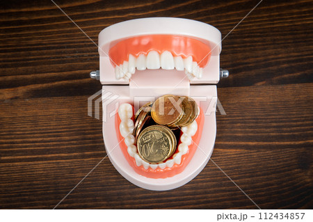 Teeth model and money on a wood texture background. Health and wellness Teeth model and money on a wood texture background. Health and wellness 112434857