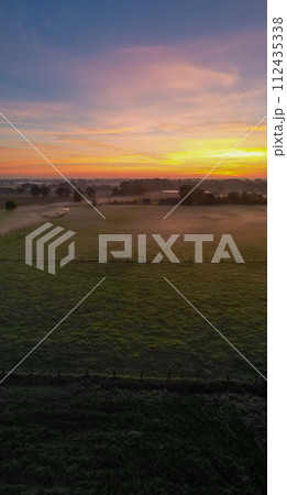 Pastoral Dawn: Serene Sunrise Over a Tranquil Countryside 112435338