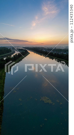 Serenity at Sunrise: Reflective Waters and Skies at Dawn 112435340