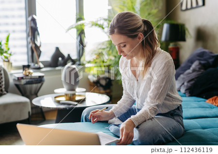 Nurse paying bills online, working on notebook. Doctor working from home, after workday, telemedicine consultation. Work-life balance for healthcare worker. 112436119