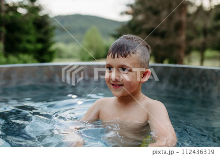 Little boy enjoying summer time in outdoor pool with his family, having fun. 112436319