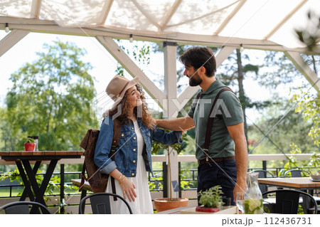 Friends meeting at a restaurant terrace. Greeting, hugging, after long time of not seeing each other. Concept of long-term friendships. 112436731