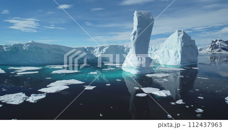Towering melting iceberg global warming concept. Snow covered glacier float turquoise ocean water in sunny summer day. Polar climate change issue. Wild Antarctica nature environment. Close up panorama 112437963