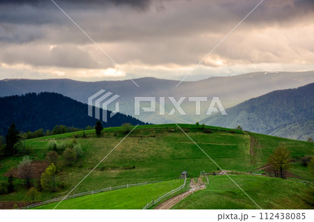 mountainous rural landscape of ukraine at sunset in spring. trees on the grassy hills rolling in to the distant valley. beautiful countryside scenery on a cloudy weather in may 112438085