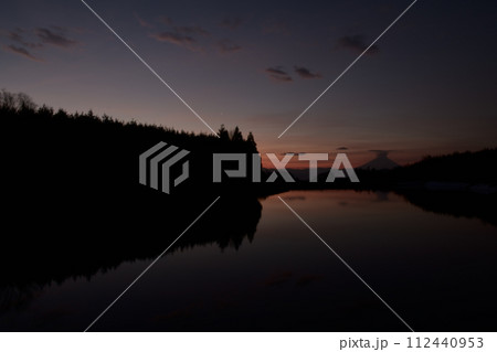 明け行く空を映す水面。林の上に昇る金星、笠雲被る富士 112440953